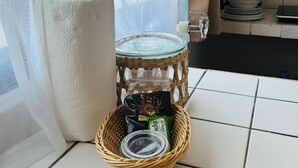 A kitchen area with a water dispenser, a roll of paper towels, and a wicker basket containing a can and a packet. - Cocoa department, unbeatable location. (puerto escondido)
