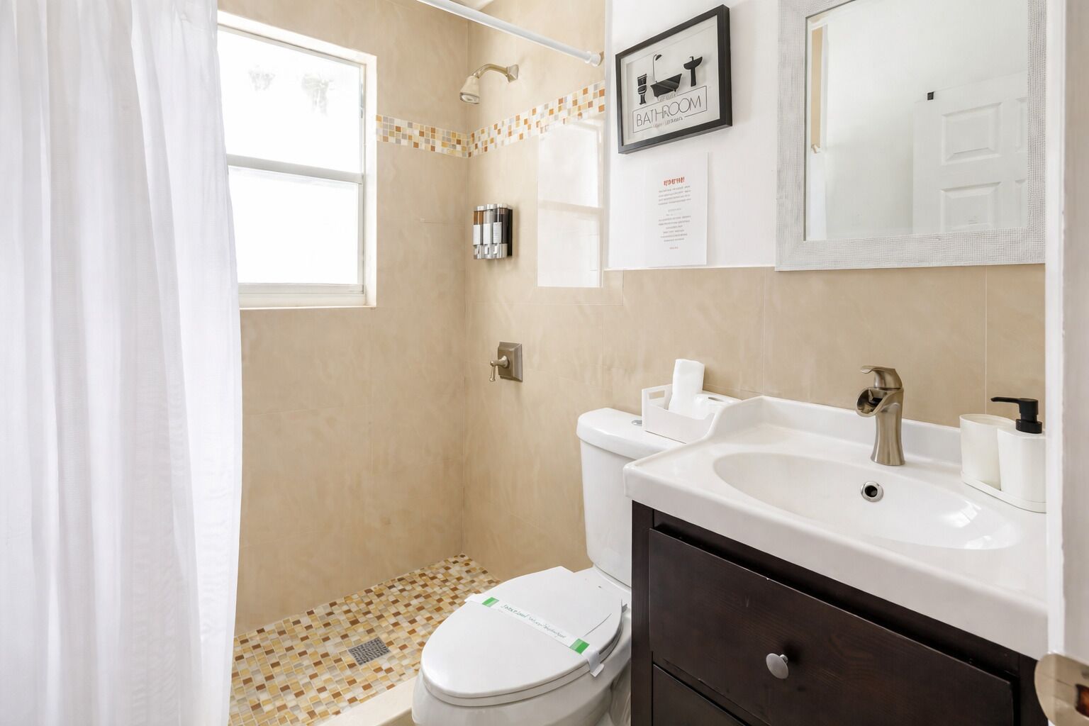 Une salle de bain équipée d’une douche, de toilettes, d’un lavabo et d’un miroir.