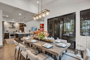 Una cocina moderna con electrodomésticos de acero inoxidable, un comedor con una mesa larga para seis personas y un amplio ventanal con vistas al exterior.