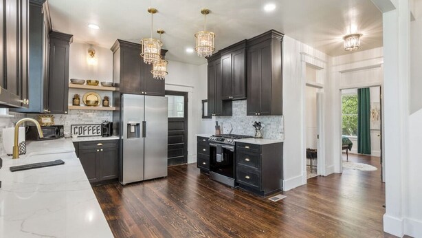 A modern kitchen with dark cabinetry, stainless steel appliances, and a marble countertop.