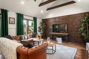 Ein Wohnzimmer mit einer Ledersofa, einem Couchtisch und einem Fernseher an einer Holzwand.