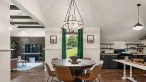 Een moderne keuken met een eetgedeelte, met een ronde tafel met stoelen, een kroonluchter en uitzicht op de omgeving.