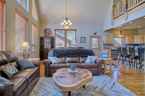A spacious living room with a leather sofa, a wooden coffee table, and a chandelier. - Snow Worries (South Fork)