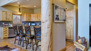 Una cucina rustica con mobili in legno, un angolo bar con poltrone in pelle e un cartello di benvenuto.