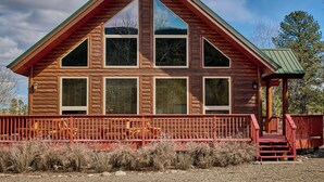 Una baita di legno con un tetto a forte spiovente, ampie finestre e un portico rosso.