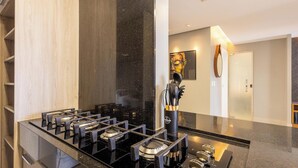 A modern kitchen with a gas stove, a black countertop, and a stainless steel backsplash. - Condominium W/pool in a Prime Location in Jardim Goias - Wsls (Goiânia)
