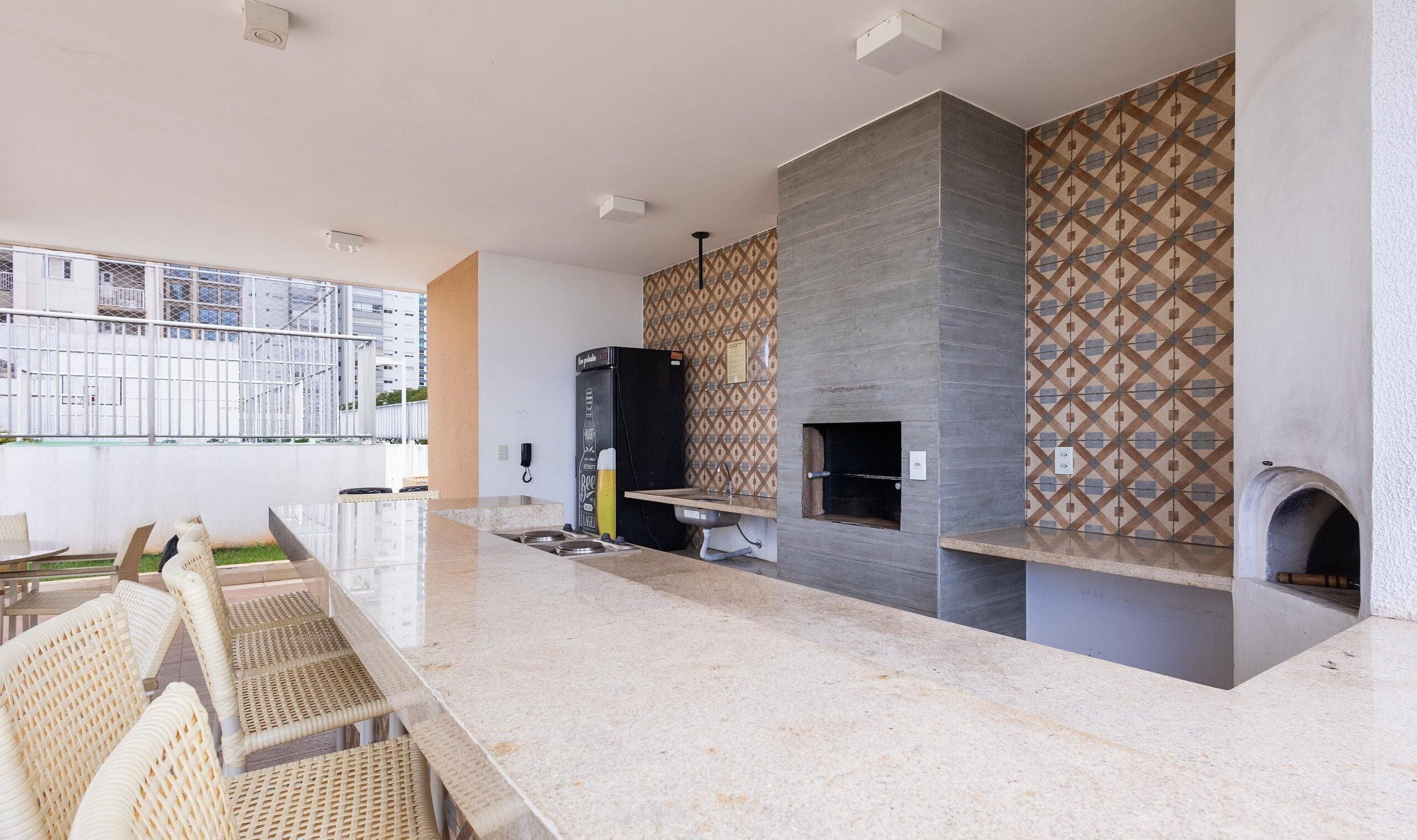 A modern kitchen with a marble countertop, a built-in oven, and a patterned backsplash.