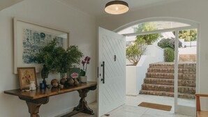 A hallway with a wooden console table, a framed artwork, and a potted plant. - Links Crescent | Contemporary Coastal Sanctuary (Cape Town)
