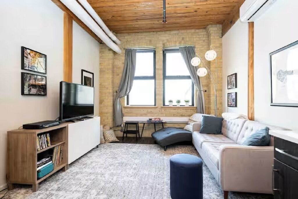 Una sala de estar acogedora con un sofá, un televisor, una estantería y un escritorio.