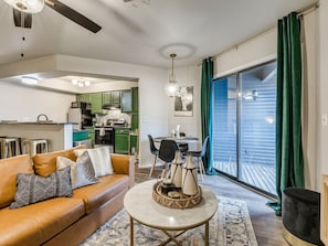 A living room with a sofa, a round coffee table, and a dining area with chairs and a table. - The Emerald Escape Route 66 (Tulsa)