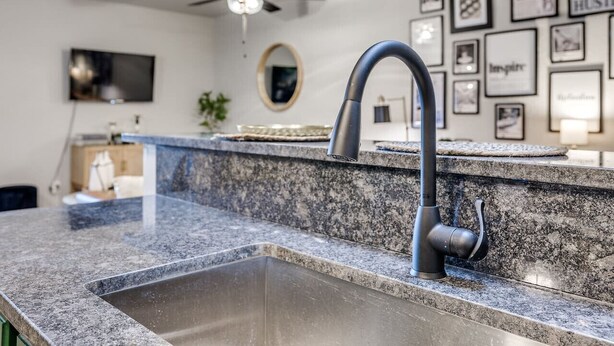 Una cocina con encimera de granito, pileta de acero inoxidable y grifo moderno.