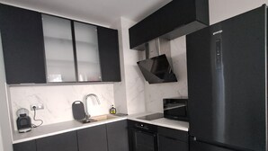 Una cocina moderna con armarios negros, un refrigerador negro y una encimera de mármol.