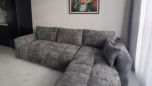 Una sala moderna con un sofá modular, un mueble negro y un cuadro enmarcado en la pared.