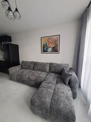 A modern living room with a sectional sofa, a black cabinet, and a framed painting on the wall. - Awesome 2-bedroom apartment with AC in charming Plovdiv (Plovdiv)