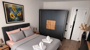 Un dormitorio moderno con cama, mesitas de noche, un armario y un cuadro en la pared.