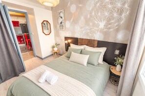 A hotel room with a bed, a bedside table, a mirror, and a view of the kitchen. - Cosy Large Apartment for 6 Guests in the Heart of Blois (Blois)