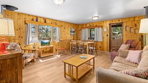 A wooden interior with a sofa, coffee table, TV, and dining area.