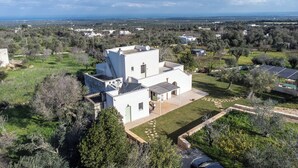 Ein modernes, weißes Haus mit Flachdach, umgeben von Grün und freiem Blick auf das Meer.