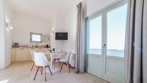 Eine moderne Küche mit Essbereich, einem Flachbildfernseher und einem großen Fenster mit Vorhängen.