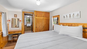 Une chambre à coucher avec un grand lit, une armoire en bois, un miroir et une fenêtre donnant sur un beau paysage.