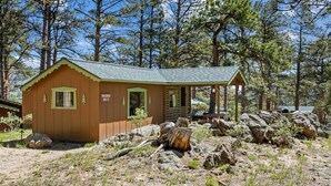 Una petita cabana amb teulada verda, amb la indicació 'MACHIN NO-3', envoltada d'arbres i roques.