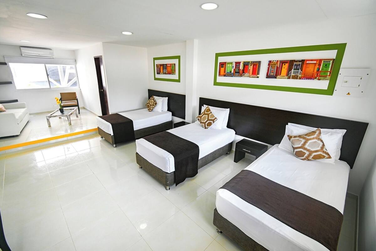 Habitación de hotel con tres camas, un sofá y una silla.