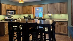 Une cuisine avec des meubles en bois, un îlot central et des luminaires suspendus.