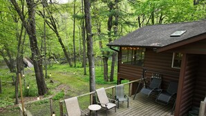 Une cabane dotée d’une terrasse, d’un espace salon extérieur et offrant une vue sur une zone boisée.