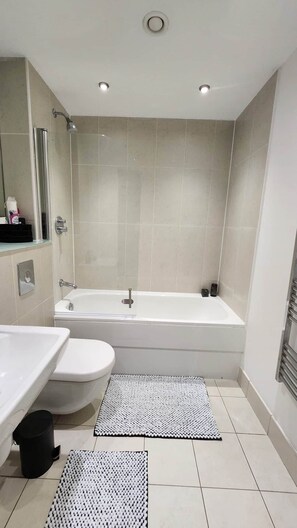 Uma casa de banho moderna com banheira, sanita e lavatório.