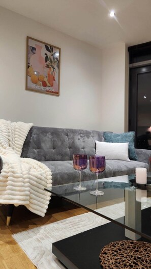 Ein modernes Wohnzimmer mit einer Couch, einem Glastisch und einem gerahmten Kunstwerk an der Wand.