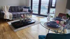 Una sala de estar moderna con sofá, mesa de centro y comedor con sillas y una mesa de vidrio.
