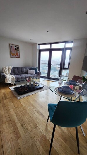 Ein modernes Wohnzimmer mit Sofa, Couchtisch und Essbereich mit Stühlen und einem Glastisch.