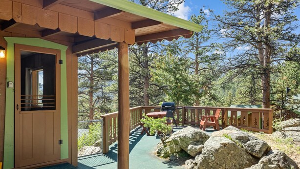 Eine Holzhütte mit Veranda, einem kleinen Tisch und einem Stuhl.