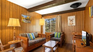 Un intérieur en bois comprenant un canapé, des fauteuils, une table et un téléviseur.