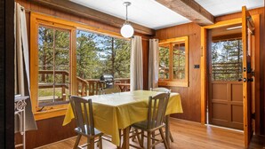 Un intérieur en bois avec une table à manger, des chaises et de grandes fenêtres.
