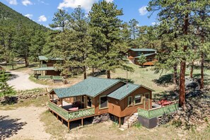 A cabin with a porch, a deck, and a small outdoor seating area.