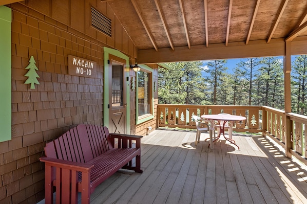 A wooden deck with a bench and table, a sign reading 'MACHIN NO-10', and a view of trees.