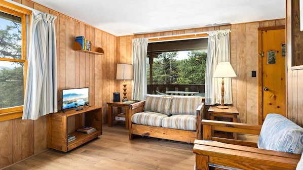 A wooden interior with a TV, sofa, and lamp.