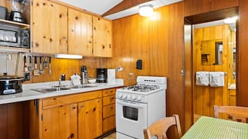 A kitchen with wooden cabinets, a stove, a sink, and a table with a green checkered tablecloth.