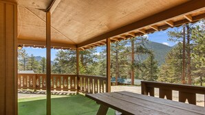 A covered outdoor area with a picnic table and a view of a mountainous landscape.