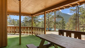 A covered outdoor area with a picnic table and a view of a mountainous landscape.