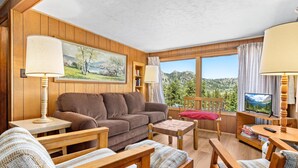 A cozy living room with wooden furniture, a sofa, a coffee table, and a TV.