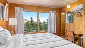 A wooden room with a bed, a desk, and a chair.