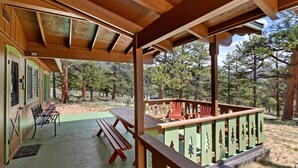 A covered outdoor area with a picnic table, benches, and a railing with tree cutouts.