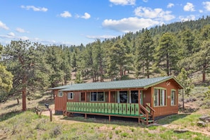 A cabin with a porch, a small deck, and a view of a forested hillside.