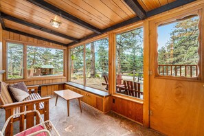 A wooden interior with large windows, a bench, and outdoor seating.