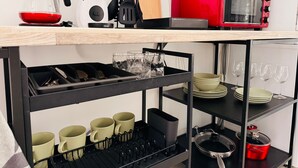 A kitchen with a coffee maker, toaster, and various utensils on the countertop.