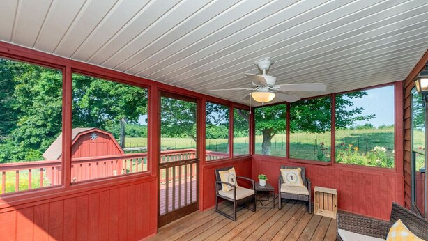 A covered porch with wicker furniture, a ceiling fan, and a view of a red barn and green landscape. - Smoky Mountain Hideaway | Spacious Yard & Firepit (Maryville)