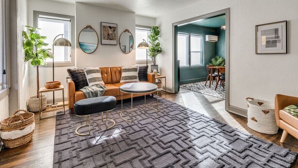 A spacious living room with a sofa, armchair, and coffee table, a large rug, and a view into another room. - Rockford`s hidden gem (Tulsa)