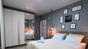 Quarto com cama, guarda-roupa, espelho e luzes na parede.